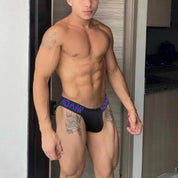 Black Adannu low-waist hip briefs with purple waistband, designed for comfort and style, modeled in a standing pose.