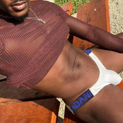 Adannu white low-waist hip briefs with purple waistband, styled for a modern and comfortable look in outdoor lighting.