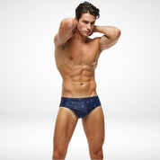 Side angle of men's navy blue swim briefs with palm tree design, made from quick-dry spandex and polyester for flexibility and comfort.