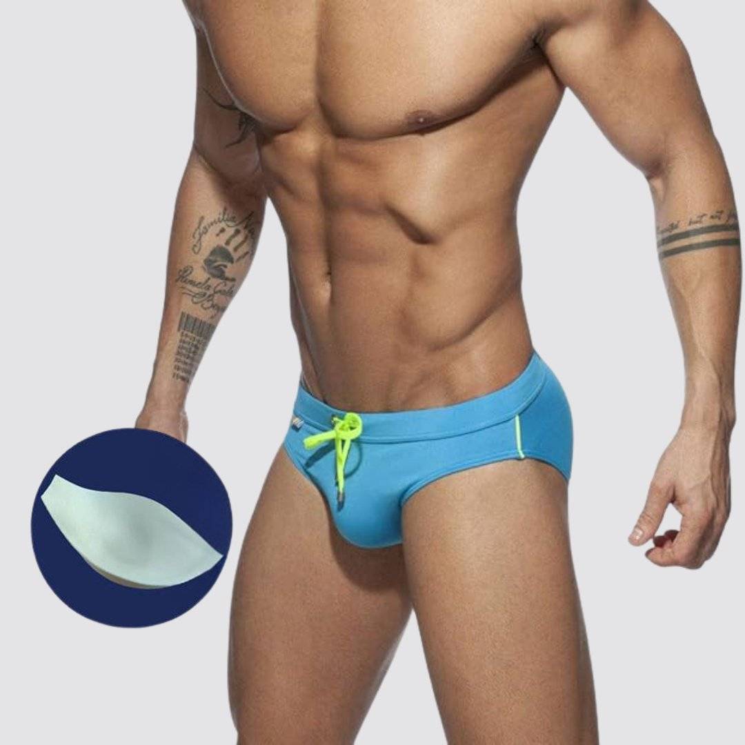 Blue swim briefs with optional enhancement pad, neon green drawstring, and rainbow detailing for a bold look.