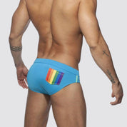 Men's blue swim briefs with a colorful rainbow back pocket, showcasing a low-rise fit and quick-dry fabric.