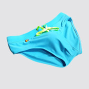 Flat-lay of blue swim briefs with neon green drawstring and rainbow detailing, made from quick-dry fabric.