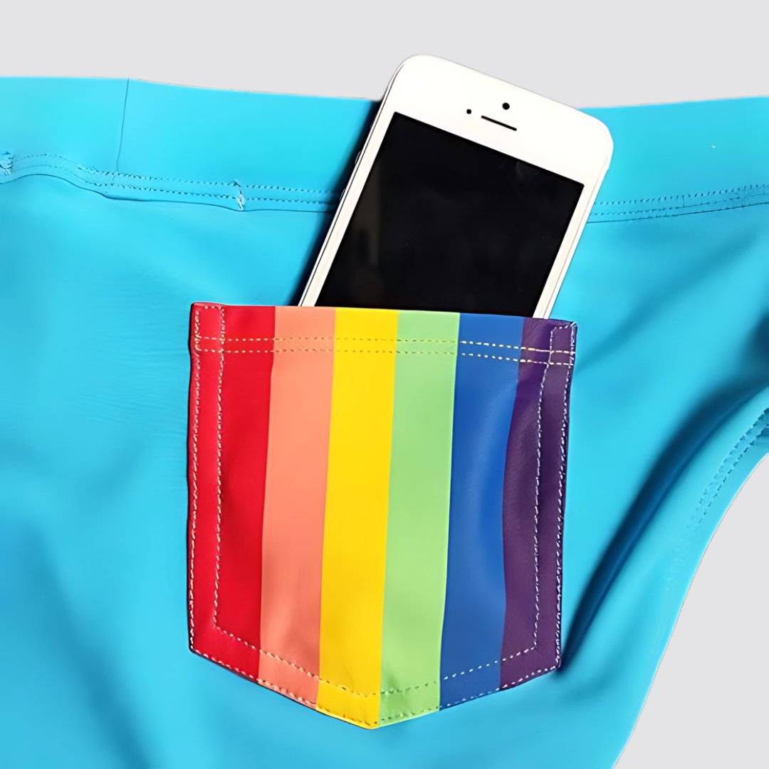 Close-up of a rainbow back pocket on blue swim briefs, holding a smartphone for added functionality.