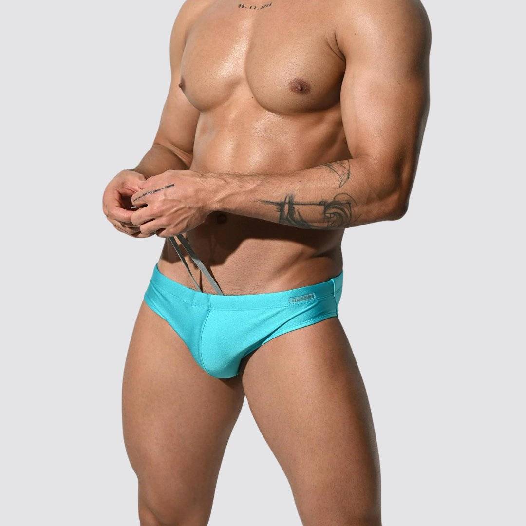 Men's shimmer low rise swim briefs in turquoise, side view with drawstring detail and stretchy, form-fitting material.