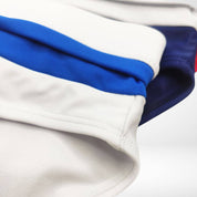 Close-up of white swim briefs with blue accents, showcasing the smooth fabric and precise stitching details.